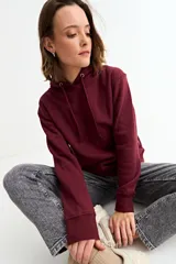 Canguro liso de color bordó, con capucha ajustable mediante cordones y bolsillo frontal tipo canguro.