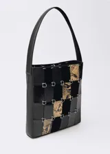 Bolso de hombro con diseño patchwork que combina paneles de cuero negro liso, cuero negro texturizado y cuero con estampado de serpiente. Presenta una estructura rígida unida por anillas metálicas plateadas y cuenta con una única asa superior.