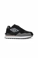 Championes Umbro Urban de estilo deportivo, color negro con refuerzos en gamuza gris en la puntera y el talón. Presenta el logo de la marca en el lateral en color blanco, entresuela blanca con una línea gris y suela dentada negra.