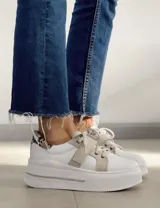 Sneakers de mujer estilo deportivo y urbano, color negro con detalles en beige claro. Presentan puntera y talón en negro, cuerpo principal en negro, y estrella lateral, cordones y tira de velcro en beige claro. La suela es blanca y el interior negro con la inscripción "LUCY IN THE SKY".