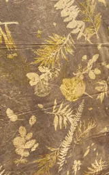 Mantel rectangular grande de algodón con estampado botánico en tonos dorados sobre fondo marrón.