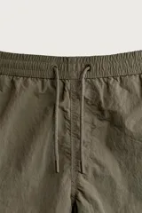 Short de baño de color azul marino, confeccionado en tejido técnico, con cintura elástica ajustable mediante cordón, bolsillos laterales y detalle de bolsillo trasero.