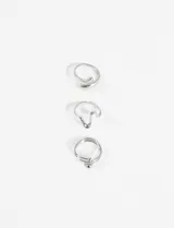 Set de tres anillos plateados de diseño moderno y orgánico, con formas onduladas y detalles de esferas.