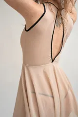 Vestido corto nude de malla transparente con bordes en contraste negro, diseño ajustado con body incorporado y falda evasé ligera.