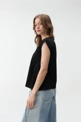 Remera negra sin mangas, de corte holgado, con hombreras marcadas y cuello redondo.