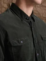 Camisa de pana color azul marino, con mangas largas, cuello clásico y dos bolsillos frontales con solapa y botón.