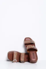 Sandalias de plataforma color marrón camel, con dos tiras en el empeine decoradas con hebillas metálicas plateadas y tachas. Suela plana y corrida.