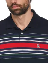 Polo de hombre azul marino con rayas horizontales rojas, blancas y verdes en la parte superior, y logo de pingüino bordado en el pecho.