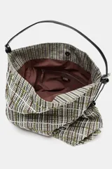 Bolso tipo shopper de tejido con diseño de cuadros en tonos verdes, blancos y marrones, decorado con apliques brillantes. Cuenta con asa de hombro ajustable en material sintético negro, cierre mediante botón imantado y bolsillo interior con cremallera.