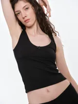 Musculosa de punto pointelle color gris melange, con escote redondo, detalle de picot en los bordes y una pequeña moña decorativa en el centro del pecho.