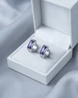 Aros tipo argolla de acero con diseño de medio aro y detalle de circonia color violeta en el centro.