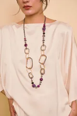 Collar largo de diseño artesanal compuesto por eslabones metálicos geométricos dorados combinados con cuentas de cristal y abalorios en tonos morados, fucsias y grises.