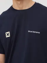 Camiseta de manga corta en color azul marino, con cuello redondo y corte clásico. Presenta un pequeño estampado en el pecho que incluye el logo de la marca y una cruz dentro de un cuadrado.