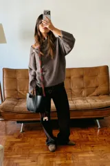 Jersey de punto color marrón topo, con cuello drapeado decorado con un broche metálico dorado y mangas largas de corte holgado.