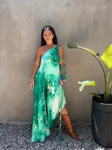 Vestido largo verde con diseño estampado tipo tie-dye y detalles dorados, de corte fluido, un solo hombro y diseño amplio.