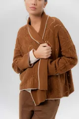 Saco tejido de lambswool color marrón, con diseño inspirado en kimono, mangas largas y delicados calados en toda la prenda. Cuenta con bordes en contraste.
