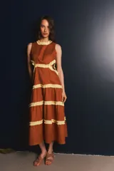 Vestido largo color marrón con volados amarillos en cuello, cintura y ruedo. Presenta recortes laterales en la cintura.