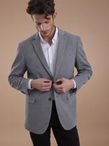Blazer formal color negro, confeccionado en tela texturada, con solapas clásicas, cierre de dos botones frontales y bolsillos con solapa.