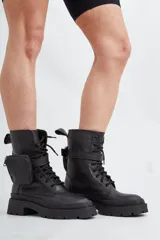 Borcego negro de cuero con base de goma track y detalle de bolsillo con cierre en el lateral.