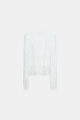 Chaqueta de cuello redondo y manga larga con hombreras, completamente cubierta de flecos con lentejuelas. Cuenta con forro interior y cierre frontal.