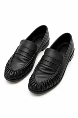 Mocasines de cuero negro con diseño clásico, punta redondeada con costuras fruncidas y tira decorativa en el empeine.