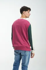 Buzo color crudo con mangas ranglan, puños y cintura acanalados. Presenta mangas color marrón y negro, y logo bordado con el número 1955 en el pecho.