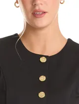 Chaleco sin mangas color negro, con cuello a la base y cierre frontal mediante botones metálicos dorados. Presenta un diseño entallado con lazo de ajuste en la espalda.
