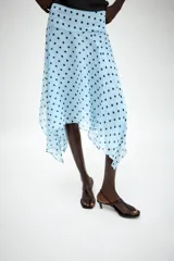 Falda midi de tiro medio color celeste con estampado de lunares negros, diseño asimétrico y forro interior. Cuenta con cierre lateral de cremallera oculta.