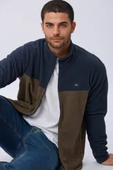 Campera polar bicolor de diseño texturado suave al tacto, con cuello alto, cierre frontal completo y bolsillos laterales. Presenta una combinación de color azul marino en la parte superior y marrón en la inferior, con un pequeño logo bordado en el pecho.
