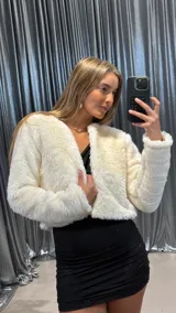 Chaqueta corta de piel sintética en color blanco, con diseño de manga larga y corte abierto sin cierre frontal.