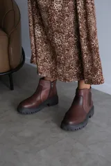 Bota corta de cuero color marrón con suela track dentada y cierre lateral.