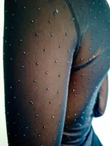 Body de manga larga confeccionado en microtul color marrón con detalle de strass plateado distribuido en toda la prenda. Presenta escote en V profundo y cierre inferior con broches.