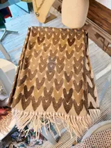 Pashmina rectangular con diseño de corazones entrelazados y flecos en los extremos.