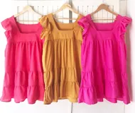 Vestido corto de lino color rosa, con escote cuadrado, mangas cortas con volados y falda escalonada.