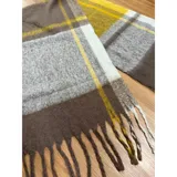 Bufanda rectangular de tejido grueso con diseño de cuadros en tonos azul, naranja, gris y beige, terminada con flecos en los extremos.