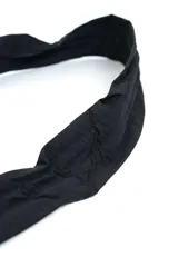 Bandolera negra acolchada de diseño curvilíneo tipo media luna, con correa ajustable integrada y cierre superior.