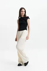 Pantalón de vestir de tiro alto, color crema, con textura crepe arrugada y pierna ancha y fluida. Presenta cintura elástica.