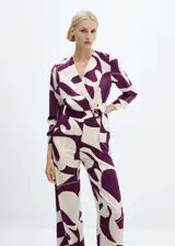 Mono largo de poliéster con estampado abstracto en tonos morado y blanco. Diseño cruzado con cuello pico y solapa, manga larga abotonada, cinturón desmontable y forro interior.