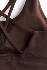 Top deportivo color marrón oscuro, de sujeción media, con escote redondo y breteles dobles finos cruzados en la espalda. Posee copas forradas con relleno extraíble y elástico cepillado en el bajo.