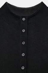 Chaqueta de punto extrafino color negro con cuello redondo y manga larga. Cierre frontal con hilera de botones pequeños.