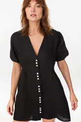 Vestido corto negro de lino italiano, con escote en V, mangas cortas abullonadas y cierre frontal de botones con cintura entallada y tablas.