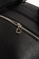 Mochila de diseño combinado en tonos tostado y marrón claro, con detalles en negro y asa superior.