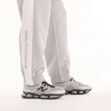 Pantalón deportivo New Balance de hombre, modelo Trackside, color gris con cintura elástica, puños ajustados en los tobillos y pequeño logo bordado en la pierna izquierda.