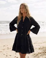 Vestido corto de lino natural color gris, con diseño amplio de capas, escote en V con botones frontales y mangas largas con volados en los puños.