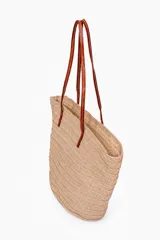 Bolso tipo capazo color beige con diseño trenzado y asas largas de cuero sintético marrón.
