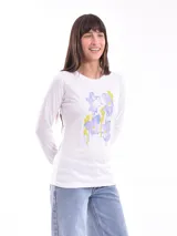 Remera de manga larga color blanco, con cuello redondo y estampado floral abstracto en tonos violeta y amarillo en el frente.