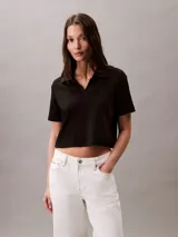 Remera tipo chomba cropped color negro, de algodón acanalado, con cuello polo, cartera abierta y logo bordado en el pecho.