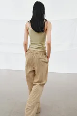 Pantalón de tiro medio con diseño de rayas verticales en tonos beige y marrón. Presenta una cintura elástica ajustable con cordones, bolsillos laterales ocultos y corte de pierna recta con aberturas en el bajo.