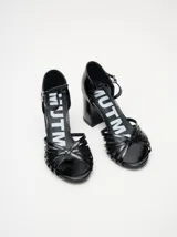 Sandalias de taco alto ancho con diseño retro, confeccionadas en charol negro. Presentan tiras delanteras múltiples entrelazadas, talón cerrado y una correa fina ajustable al tobillo con hebilla metálica.