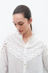 Camisa blanca de manga larga con cuello mao y puntilla calada en el frente y puños.
